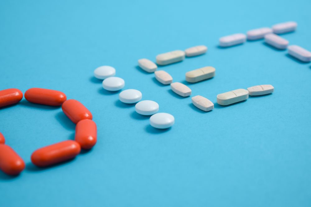 Various pills spelling the word "DIET" on blue table