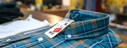 Close up of label with discount price over a blue plaid shirt on vintage store