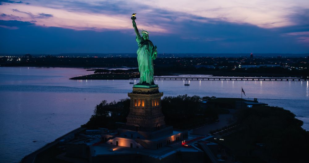 Aerial Image of the Statue of Liberty. Helicopter Shot of the Patriotic Monument in Beautiful Sunset Setting, Standing on a Liberty Island in New York City Harbor