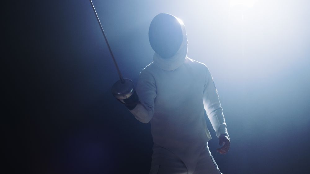 Fully Equipped Fencer Puts Lifts Foil Sword in Readiness for a Match.