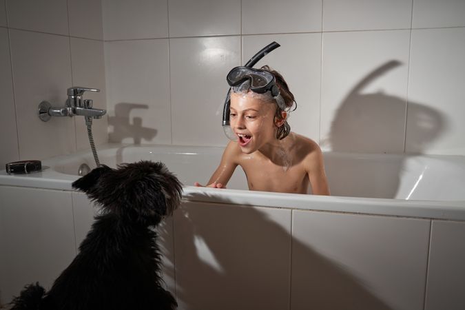 Funny boy in tub near dog
