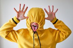 Anonymous child in hoodie mocking on gray backdrop