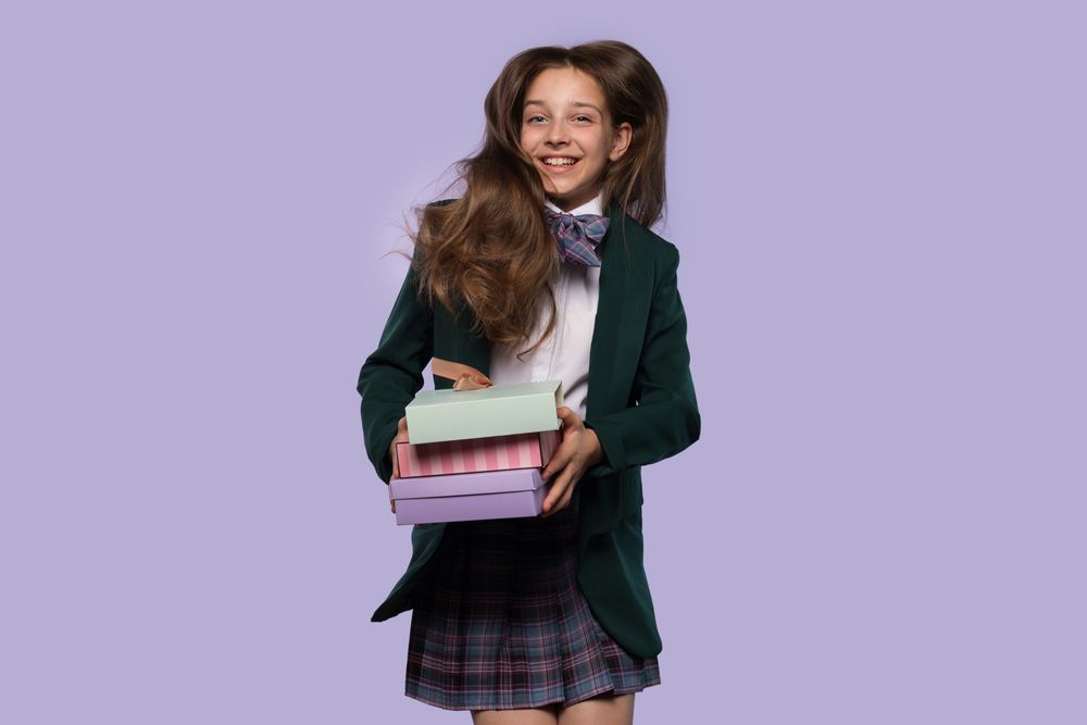 Schoolgirl holding colorful gift boxes while smiling.