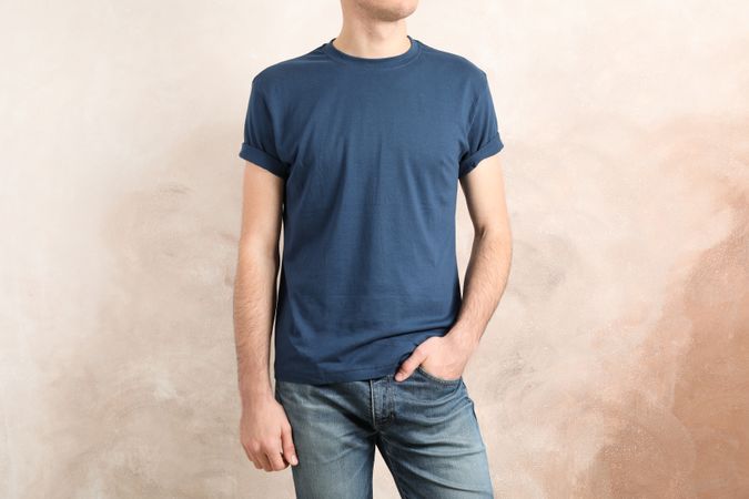 Men in blank blue t-shirt against brown background, space for text