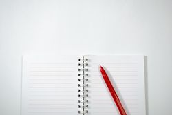Open notebook and red pen isolated on plain background