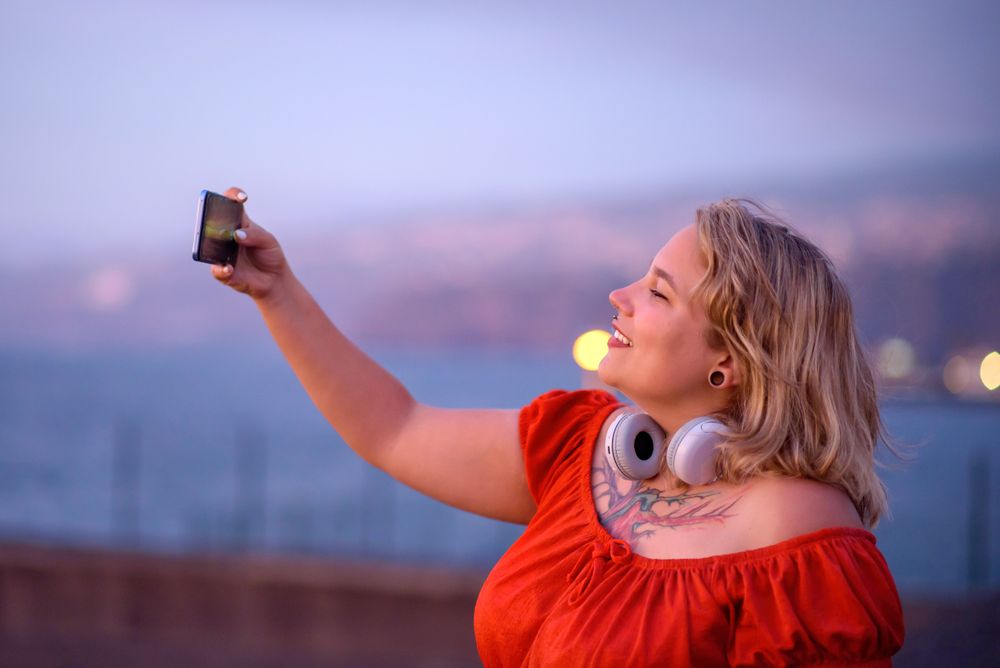 Positive woman taking selfie on smartphone