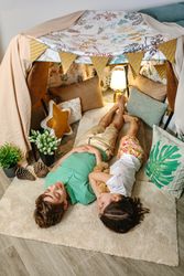 Two children sleeping lying over rug in cozy tent at home with warm and playful atmosphere