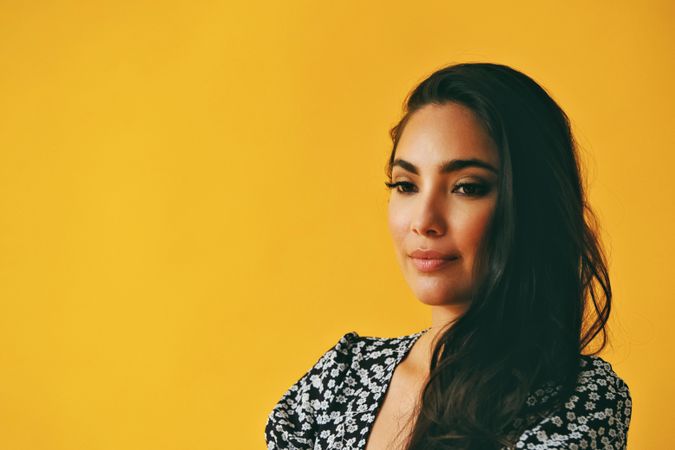 Sad Hispanic woman wearing dress in yellow room