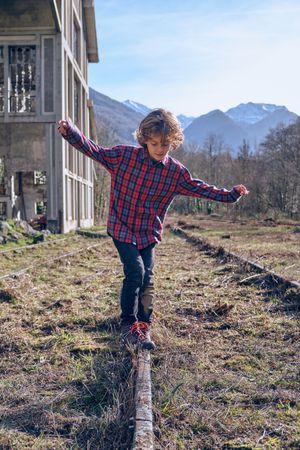 Boy spreading arms while balancing on rail in suburb area