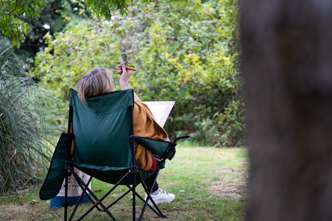 Back of woman sitting calmly outside drawing