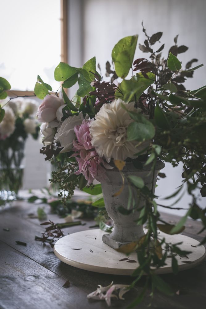 Composition of flowers and plants in vintage vase on board