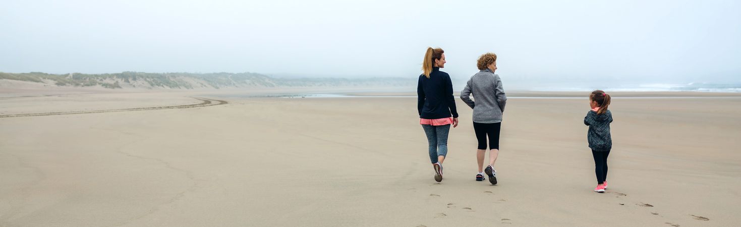 Three generations of women walking on the beach