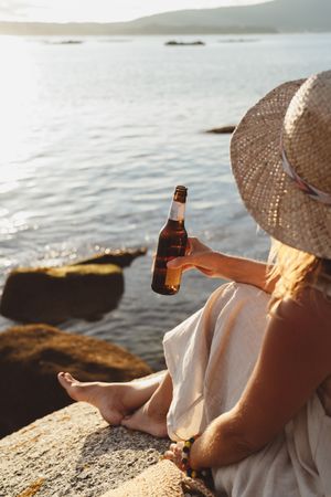 Woman relaxing and drinking beer at beach