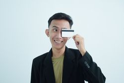 Asian young businessman wearing suit with tshirt and holding blank credit card