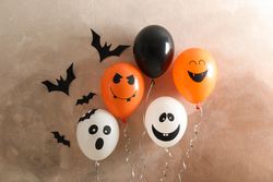 Different balloons on brown background. Halloween concept, space for text