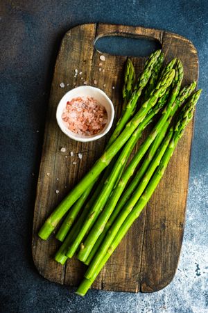 Raw asparagus on wooden board with Himalayan salt