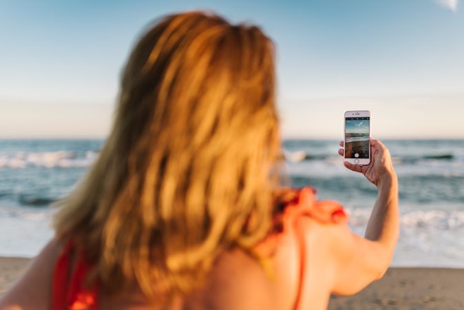 Woman in red dress taking photo on smartphone