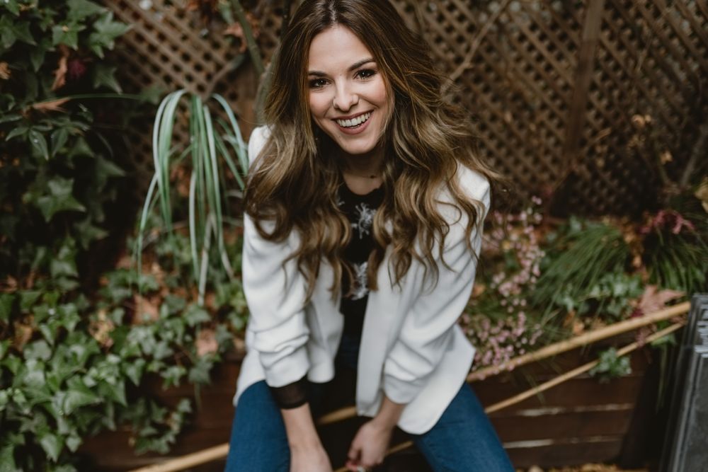 Smiling woman sitting on planter in garden