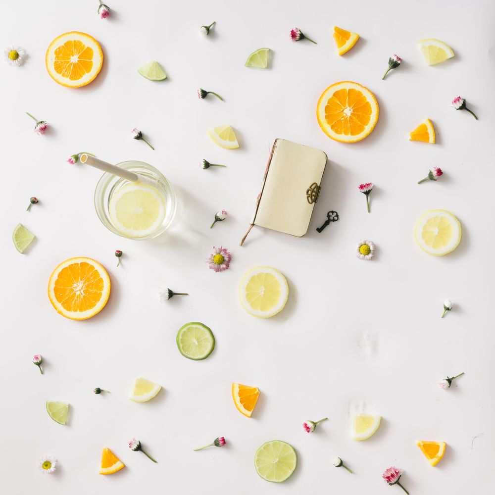 Colorful pattern made of orange, lemon, lime and flowers with lemonade and vintage book with key