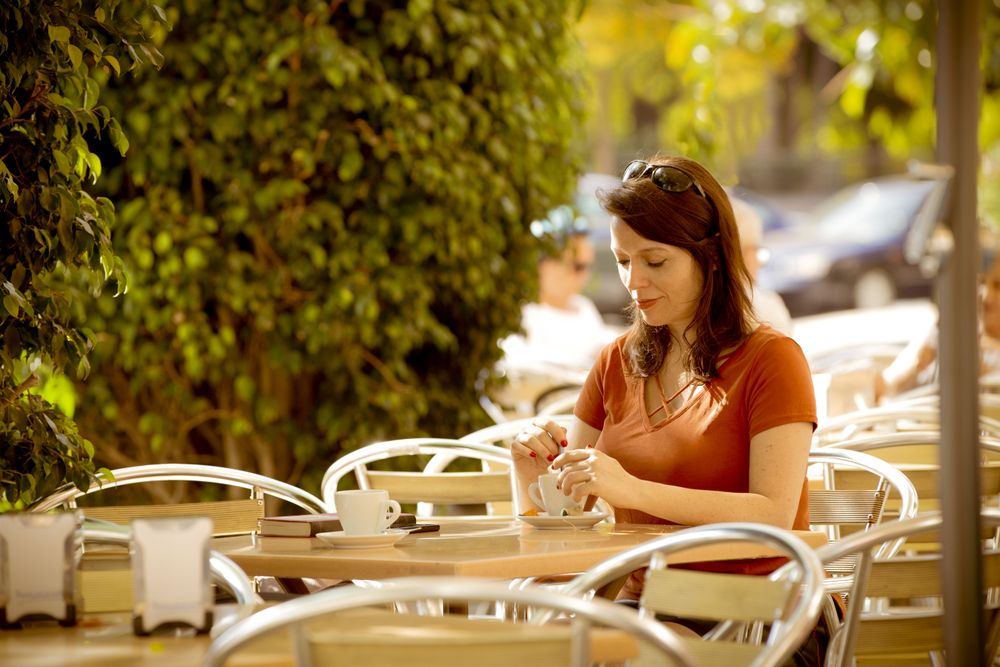 Adult female having tea in summer cafe
