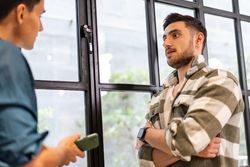 Two colleagues standing by window discussing work