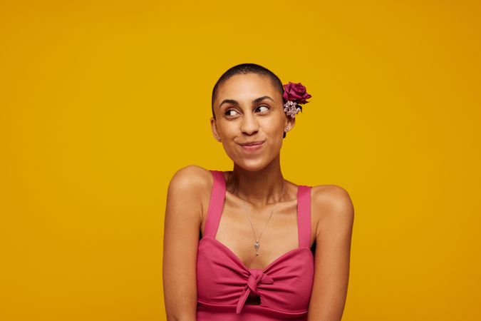 Pretty female model with shaved head on yellow background