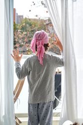 Kid with pink headband looking out glass door at home