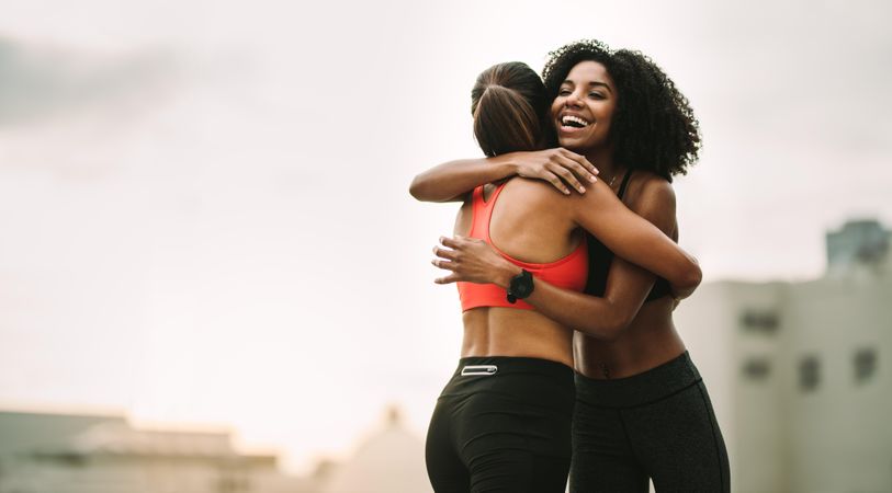Cheerful female athletes embracing each other after workout