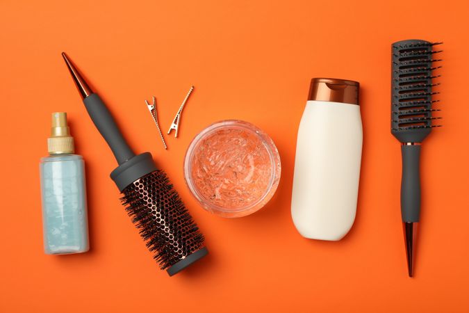 Composition with hairdresser accessories on orange background, top view