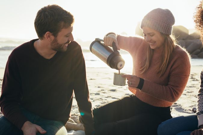 Smiling friends having coffee at the beach