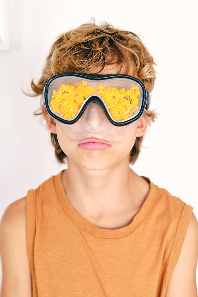 Boy in diving mask with petals on light background