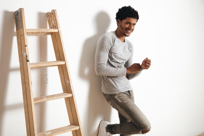 Side view of man smiling standing next to ladder