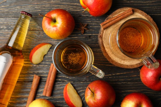 Composition with cider, cinnamon and apples on wooden background