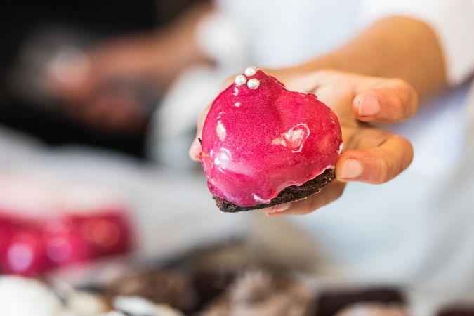 Crop baker with sweet cake in shape of heart