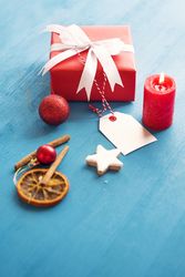 Red gift box with tag on table with cinnamon and a candle