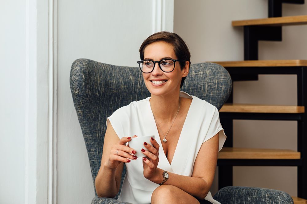 Happy woman sitting near stairs with a coffee