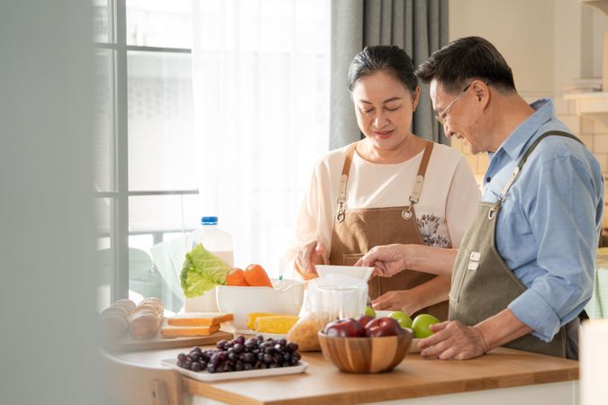 Asian mature couple cooking breakfast in the kitchen