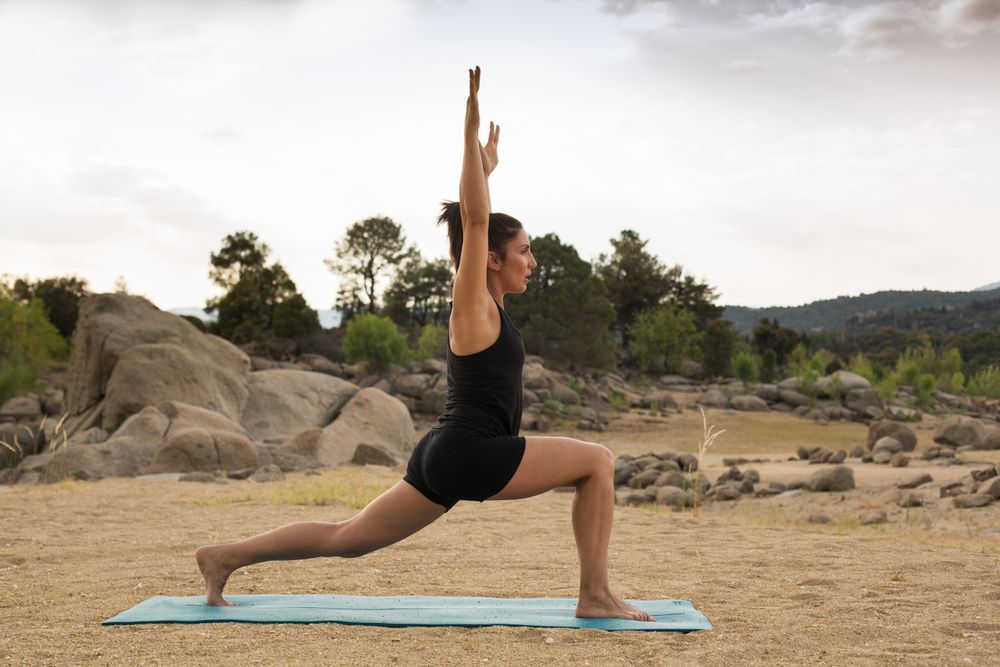 Woman practicing yoga outdoors near water