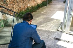 Back of man checking digital tablet on stairs
