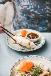 Man holding spring roll between chop sticks