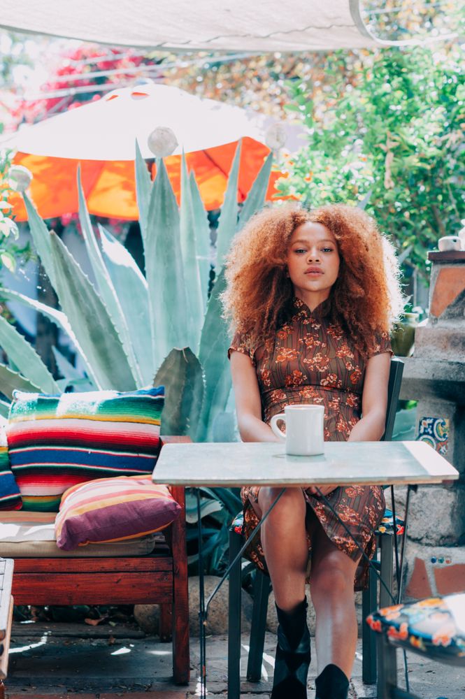 Young Black woman with afro sitting outside looking at camera