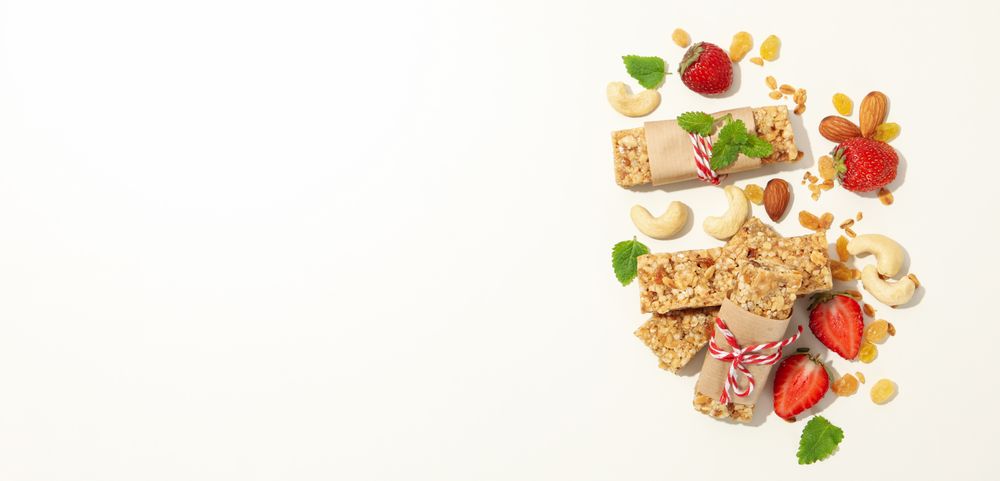 Granola bars, strawberry and nuts on blank background, space for text