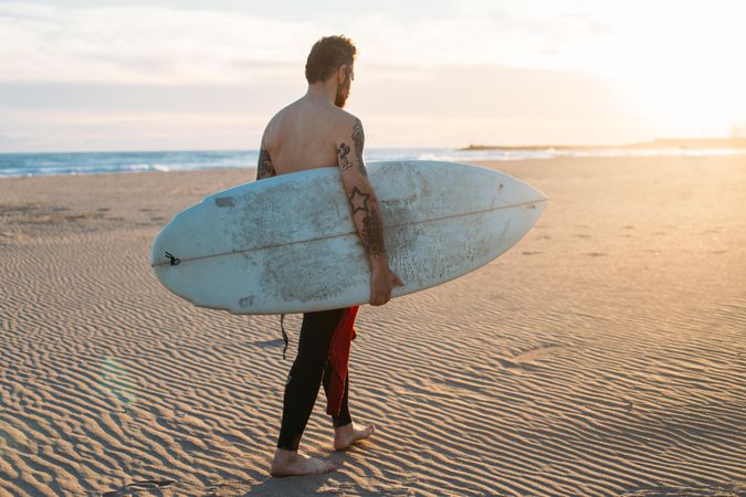 Man walking along beach with surfboard