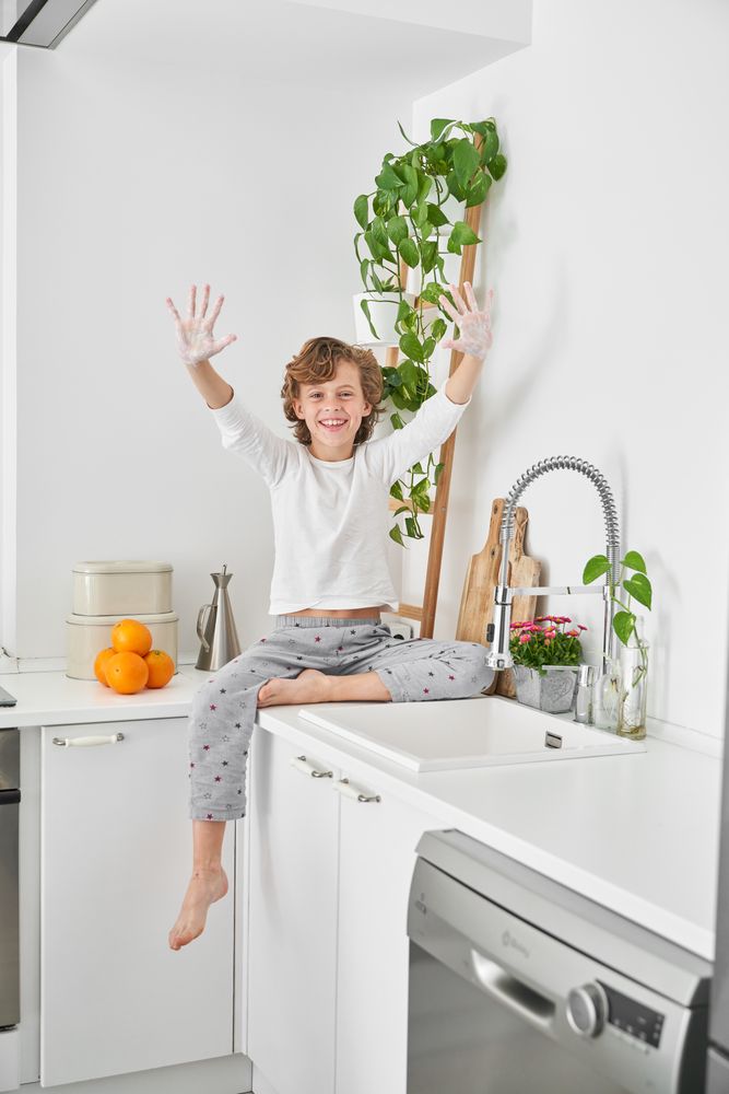 Cheerful boy showing soapy palms while cleaning hands in kitchen