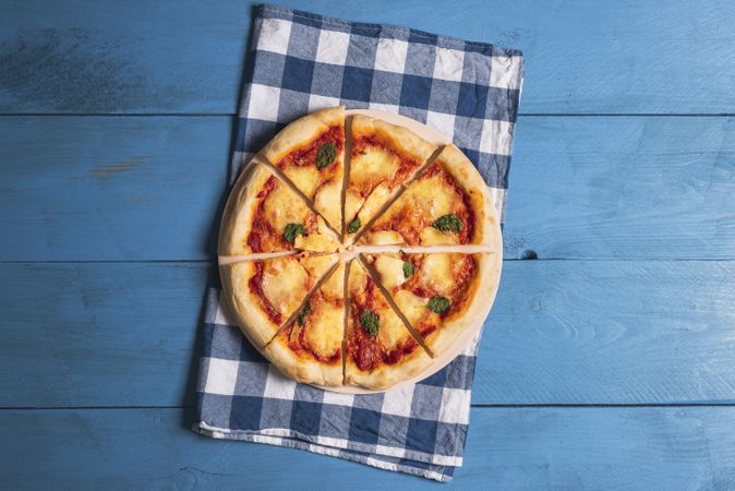 Sliced pizza Margherita on blue napkin and wooden table