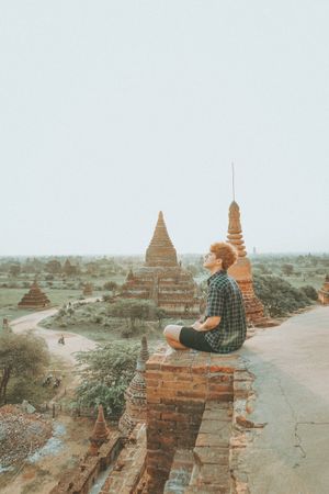 Young man sitting on ground near temples