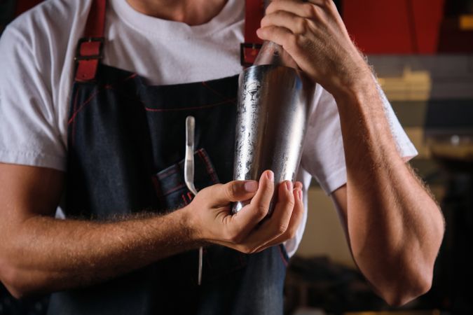 Unrecognizable barman preparing cocktail in cobbler shaker