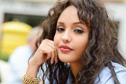 Female with long curly hair resting her face on her hand