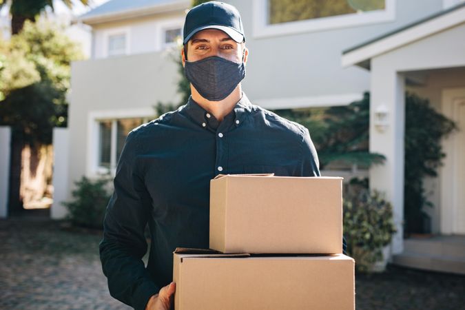 Delivery man with face mask delivering parcel boxes