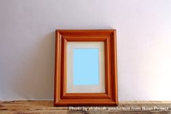 Rectangular wooden picture frame on wooden desk mockup bYoaN5